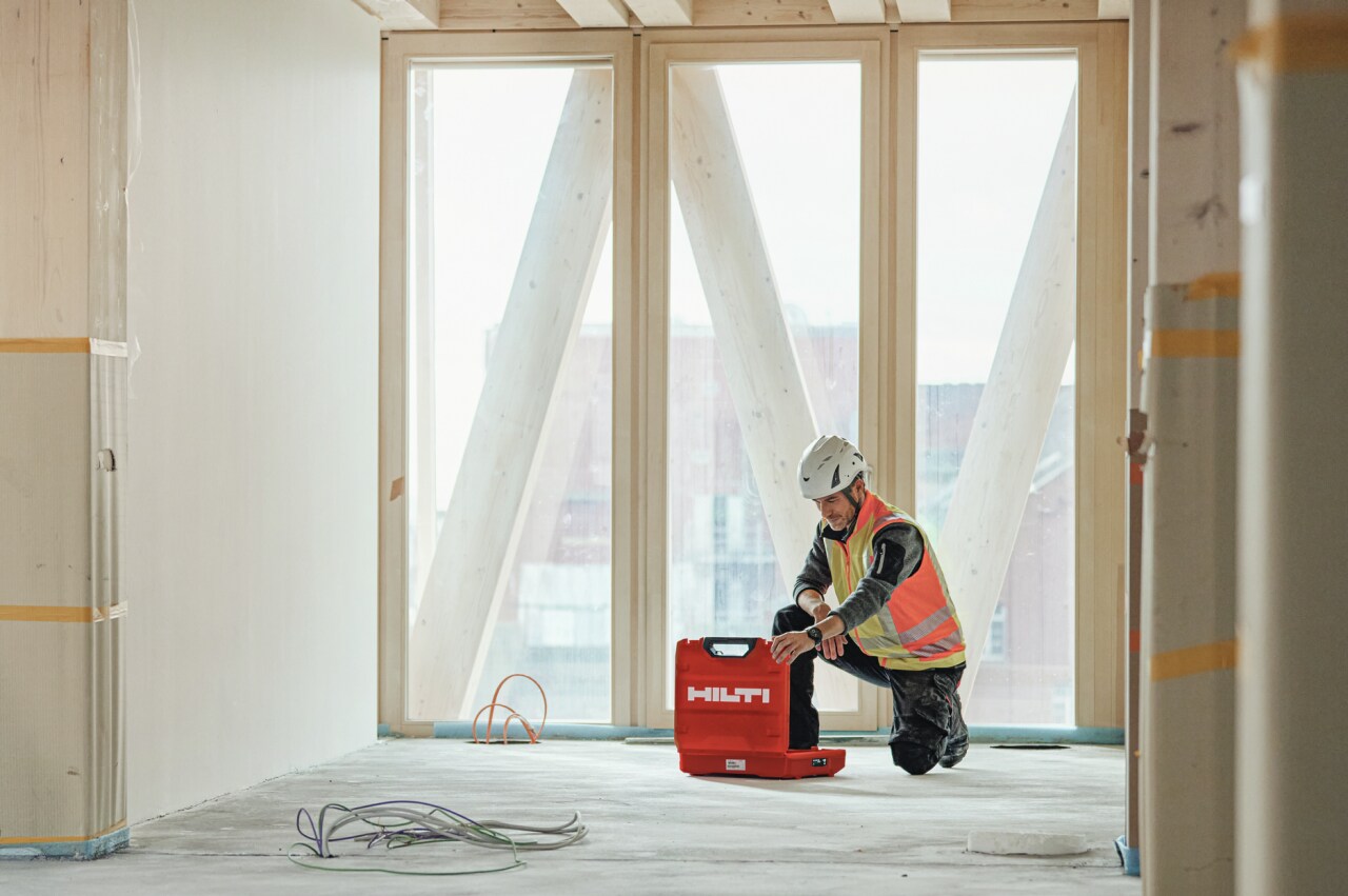 A construction worker knealling down to get a Hilti tool box in a site
